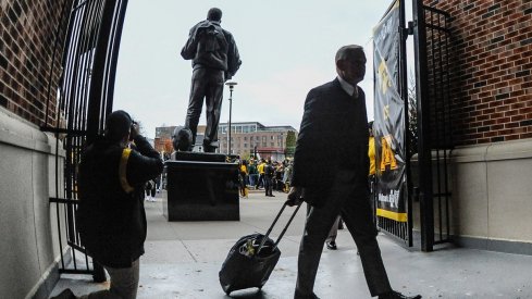 Kirk Ferentz carries a suitcase into Kinnick Stadium