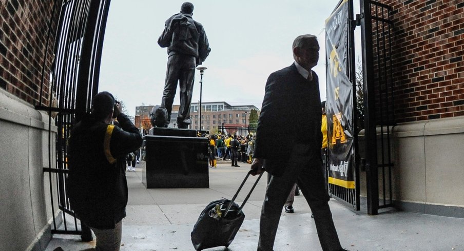 Kirk Ferentz carries a suitcase into Kinnick Stadium